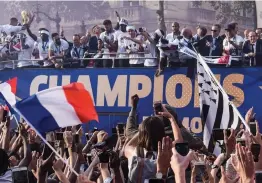  ?? — AFP ?? Fans cheer the victorious French team parading aboard a bus on the famed Champs Elysees avenue in Paris on Monday after their 4- 2 victory on Sunday over Croatia to capture the trophy in the final of the Fifa World Cup.