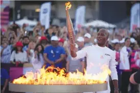  ?? AP PHOTO/DANIEL COLE ?? On Thursday, torchbeare­r Didier Drogba of France holds the torch to light the cauldron at the Velodrome stadium in Marseille, southern France.