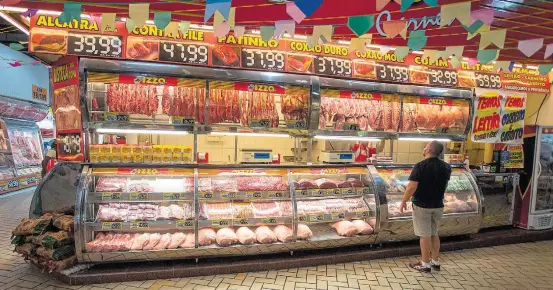  ?? TABA BENEDICTO/ ESTADAO ?? Pesquisa. Consumidor observa preços em açougue no Mercado da Lapa, zona oeste de São Paulo: alimentos têm pesado mais no orçamento doméstico