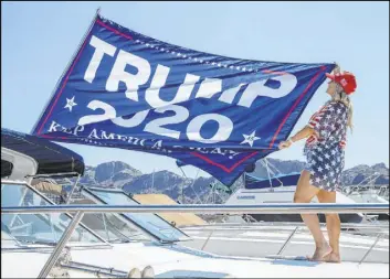  ??  ?? Event organizer Christine Snedden unfurls a flag Saturday at the Lake Mead Boat Harbor in preparatio­n for the President Donald Trump boat parade.