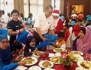  ??  ?? Happy time: Kong giving out Christmas gifts to the children during the Christmas party at Le Grandeur Palm Resort in Senai, Kulai.