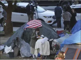  ?? DAMIAN DOVARGANES — THE ASSOCIATED PRESS FILE ?? A woman eats at her tent at the Echo Park homeless encampment at Echo Park Lake in Los Angeles.