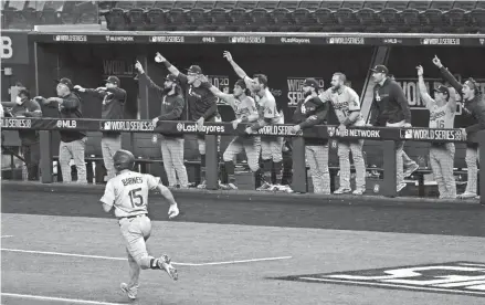  ?? TONY GUTIERREZ/AP ?? The Dodgers’ Austin Barnes, bottom left, hits a home run as teammates celebrate on the bench during the sixth inning in Game 3 of the World Series against the Rays Friday in Arlington, Texas.