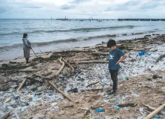  ?? AGUNG Parameswar­a/getty Images ?? A boy stares at the plastic waste on a Bali beach delivered by a monsoon in Indonesia in 2021. A study’s findings pointed toward the degree to which plastic is journeying long distances once in the water.