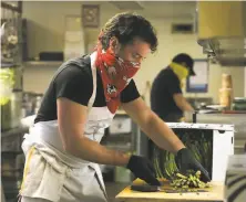  ?? Photos by Lea Suzuki / The Chronicle ?? Food Runner chef Todd Corboy, above, chops asparagus in the Haight kitchen while volunteer Florence Gong, left, ladles soup.