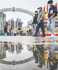  ?? JEFF MCINTOSH/THE CANADIAN PRESS ?? Mask-wearing visitors at the Calgary Stampede
grounds during the weekend.