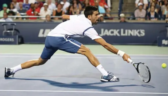  ?? STEVE RUSSELL/TORONTO STAR ?? Novak Djokovic stretches for a return in Saturday night’s straight-sets victory over Gael Monfils in the Rogers Cup semifinals. Djokovic has never lost to Monfils in 12 meetings.