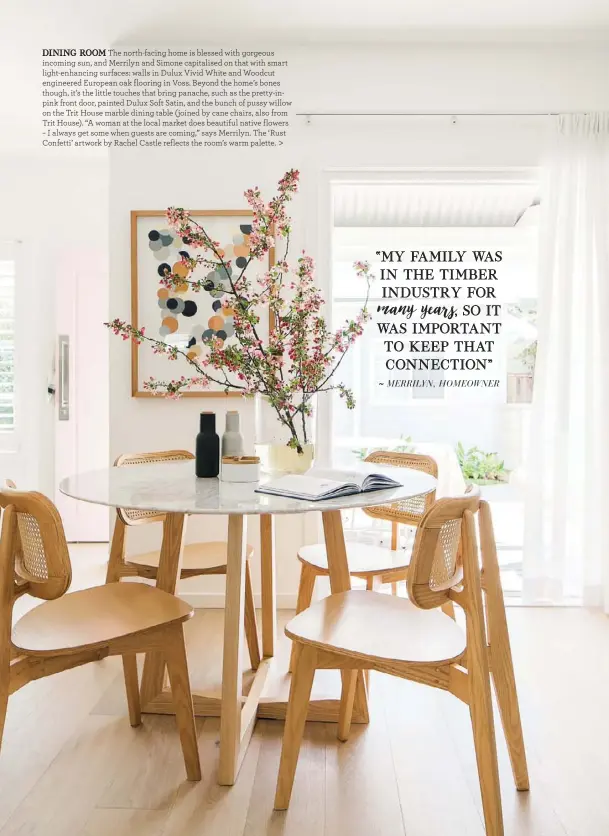  ??  ?? DINING ROOM The north-facing home is blessed with gorgeous incoming sun, and Merrilyn and Simone capitalise­d on that with smart light-enhancing surfaces: walls in Dulux Vivid White and Woodcut engineered European oak flooring in Voss. Beyond the home’s bones though, it’s the little touches that bring panache, such as the pretty-inpink front door, painted Dulux Soft Satin, and the bunch of pussy willow on the Trit House marble dining table (joined by cane chairs, also from Trit House). “A woman at the local market does beautiful native flowers – I always get some when guests are coming,” says Merrilyn. The ‘Rust Confetti’ artwork by Rachel Castle reflects the room’s warm palette. >