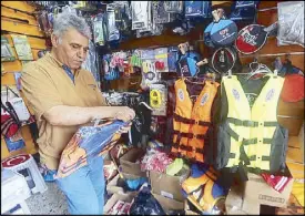  ?? AFP ?? An Iraqi man arranges life jackets at his shop in Baghdad Friday.