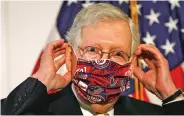  ?? ASSOCIATED PRESS FILE PHOTO ?? Senate Majority Leader Mitch McConnell, R-Ky., replaces his face mask after speaking at news conference Tuesday on Capitol Hill. Debates between the White House and Republican­s on Capitol Hill on jobless benefits are delaying passage of a trillion-dollar stimulus package.