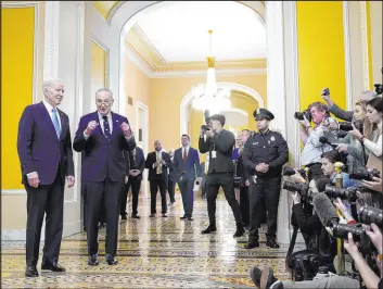  ?? Evan Vucci The Associated Press ?? President Joe Biden listens as Senate Majority Leader Chuck Schumer, D-N.Y., speaks with reporters Thursday after the Senate Democratic Caucus luncheon on Capitol Hill.