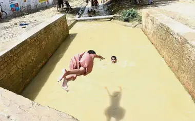  ?? — AFP ?? Cooling off: A boy diving into a stream during a hot day in Sibi.