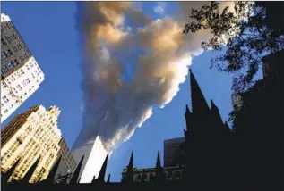  ?? Mario Tama Getty Images ?? SMOKE BILLOWS FROM New York’s World Trade Center during the Sept. 11, 2001, terrorist attacks, which left nearly 3,000 people dead. Almost 20 years later, five suspects await trial.