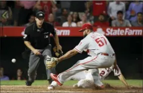  ?? JAE C. HONG — THE ASSOCIATED PRESS ?? Los Angeles Angels shortstop Andrelton Simmons scores on a wild pitch as Phillies reliever Luis Garcia awaits the throw in the eighth inning Thursday.
