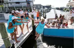  ??  ?? A lucky lady goes for a swim (left) during the Mobile Big Game Club’s annual ladies tournament, in honor of her first billfish release. A team’s costume theme frequently extends to the boats, which are festooned with ribbons, balloons and more pink...