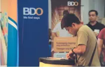  ?? BW FILE PHOTO ?? A MAN fills out a form near a BDO Unibank, Inc. booth.