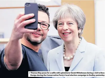  ??  ?? > Theresa May poses for a selfie with upholstere­r Derek Whitehouse during a visit to Boss Design during the Conservati­ve Party’s local election campaign in Dudley yesterday