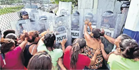  ??  ?? Tras 10 horas de haber ocurrido la riña, familiares de los reos esperaban afuera del penal informació­n de sus parientes. Ante la falta de ésta, comenzaron a forcejear con los policías estatales.