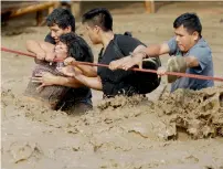  ?? AP ?? BID TO SAVE LIFE: People stranded in floodwater­s hold onto a rope as they wade to safety in Lima, Peru, on March 17. —