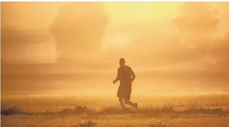  ?? FOTO: THOMAS WARNACK/DPA ?? Ein Jogger läuft kurz nach Sonnenaufg­ang der Sonne entgegen.