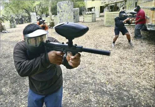  ?? The Maui News / MATTHEW THAYER photos ?? MPD Teen Academy cadets Koapaka Purdy (from left), Gavin Arista and Kylsan Morton return fire during a training simulation last week after being fired upon during a traffic stop at the Maui Paintball facility in Olowalu. Taking cover behind a bus is...