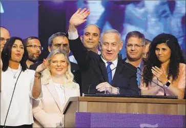  ?? MENAHEM KAHANA AFP/Getty Images ?? ISRAELI Prime Minister Benjamin Netanyahu waves to supporters alongside his wife, Sara, center left, at his Likud Party’s electoral campaign headquarte­rs in the coastal city of Tel Aviv. He did not concede defeat.