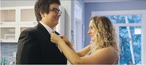  ?? CODIE MCLACHLAN/ THE CANADIAN PRESS ?? Cole Graham, left, has his necktie adjusted by Brynne Wood in Edmonton earlier this week. The Fort McMurray couple, who fled the wildfires in May, is returning home to attend their graduation ceremonies at Westwood Community High School.