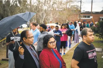  ?? Audra Melton / New York Times ?? Dr. Serajul Bhuiyan (left) and his daughter, Lamisa, 22, join fellow voters as they line up to cast their ballots in Savannah, Ga., on Friday, the last day for early voting before election day.