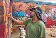  ?? (NWA Democrat-Gazette/Janelle Jessen) ?? Artist Jose Hernandez of Little Rock works on the mural he is painting on the Simmons Further Processing building at the corner of East Main Street and Hico Street in Siloam Springs. The 150-foot mural will be complete in about two weeks, weather permitting.