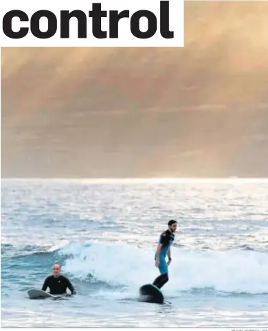  ?? MIGUEL BARRETO / EFE ?? Dos jóvenes practican surf ayer en la playa de Martiánez, en el Puerto de la Cruz en Tenerife.