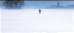  ?? A man walks across a snow-covered field on the island of Ruegen, Germany, on Sunday. (AP/Jens Buettner) ??