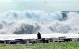  ??  ?? This CNA handout picture taken and released on September 14, 2018 shows a man watching huge waves crashing into the coast at Taitung county, eastern Taiwan, as Super Typhoon Mangkhut approaches the southern sea of Taiwan. (Photo by - / CNA / AFP)