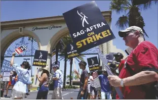  ?? CHRIS PIZZELLO/AP ?? STRIKING WRITERS AND ACTORS picket outside Paramount studios in Los Angeles on July 14.