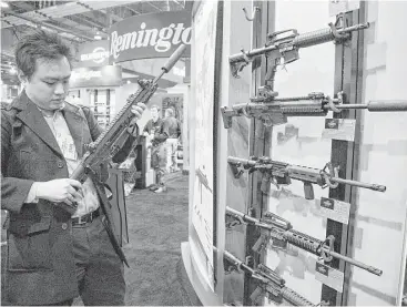  ?? Julie Jacobson / Associated Press file ?? Accessorie­s manufactur­er Kevin Kao examines a military grade Remington Adaptive Combat Rifle at a show in Las Vegas. S&P has cut the credit rating of Remington Outdoor.
