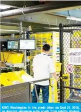  ??  ?? KENT, Washington: In this photo taken on Sept 21, 2018, an Amazon employee pulls goods from robotic shelves during a tour of Amazon’s Fulfillmen­t Center. — AFP