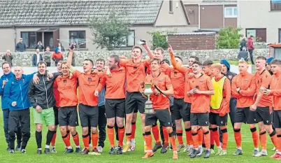  ?? ?? Jubilant Rothes players and coaching staff celebrate with the North of Scotland Cup