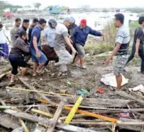  ??  ?? Residents carry a bag containing the body of a tsunami victim in Palu.