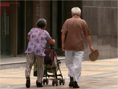  ??  ?? An elderly couple in Nanjing, Jiangsu Province, take their grandchild out, August 31, 2011