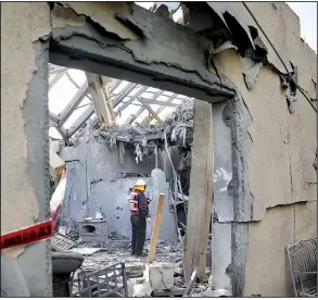  ?? AP/ARIEL SCHALIT ?? A firefighte­r examines the damage to a house in Mishmeret, Israel, on Monday after it was struck by a rocket fired from the Gaza Strip.