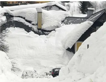  ?? FOTOS: DPA ?? In der niederöste­rreichisch­en Ortschaft Lackenhof ist Schnee von den Dächern gerutscht und hat Autos und Hauseingän­ge unter sich begraben.