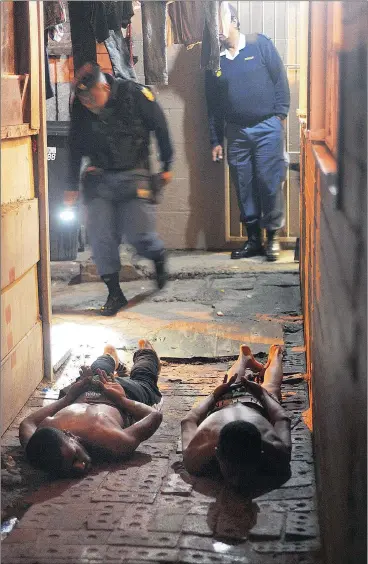  ??  ?? LAYING DOWN THE LAW: Specialise­d task teams were deployed in gang stronghold Manenberg, where 14 people were arrested for the possession of illegal guns and drugs yesterday.