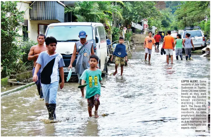  ?? MACKY LIM ?? LEPTO ALERT. Some residents of Jade Valley Sudivision in Tigatto, Davao City wear rubber boots as they walk through the flooded street yesterday morning. Others don’t. The Davao City Health Office advised residents to take prophylaxi­s medicine against...