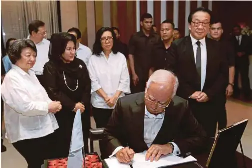  ?? PIC BY ZUNNUR AL SHAFIQ ?? Prime Minister Datuk Seri Najib Razak penning his condolence message at the late Tan Sri Yeoh
Tiong Lay’s residence in Kuala Lumpur yesterday. With him is his wife, Datin Seri Rosmah Mansor.