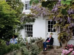  ?? (Getty) ?? Two neighbours enjoy a socially distanced chat under the wisteria on their houses in Richmond