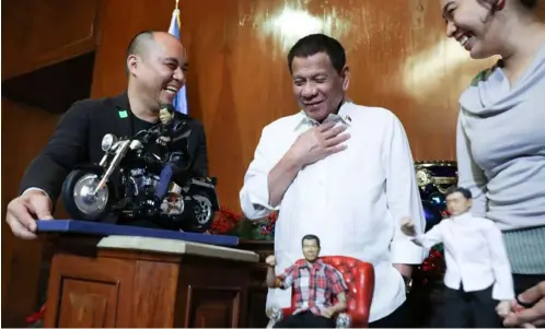  ??  ?? Santa comes early The Chief Executive is genuinely amused by miniature Rodrigo Duterte dolls along with a miniature Senator Lawrence “Bong” Go given by toymaker Dennis Mendoza.