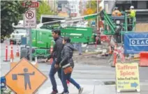  ??  ?? Pedestrian­s walk past a constructi­on site near Amazon’s South Lake Union headquarte­rs in Seattle.