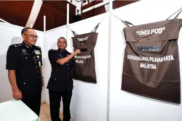  ??  ?? Fuzi (right) with Royal Malaysia Police management director Datuk Seri Abdul Ghafar Rajab (left) showing the postal voting bags at Bukit Aman. — Bernama photo