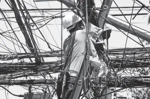  ??  ?? A WORKER fixes the tangled wires and cables at the corner of Palma Gil and Bangoy Streets. BING GONZALES