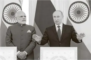  ?? Dmitry Lovetsky / pool photo via Associated Press ?? Russian President Vladimir Putin, left, and India’s prime minister, Narendra Modi, discuss a nuclear reactor deal at a forum Thursday in St. Petersburg. At the forum, Putin said Russia has never engaged in hacking.