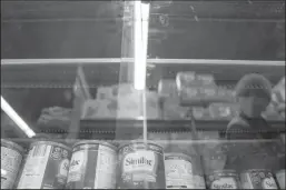  ?? STEFANI REYNOLDS/AFP VIA GETTY IMAGES ?? A shopper is reflected in a glass case while looking at baby formula at a grocery store in Washington, D.C, on May 11.